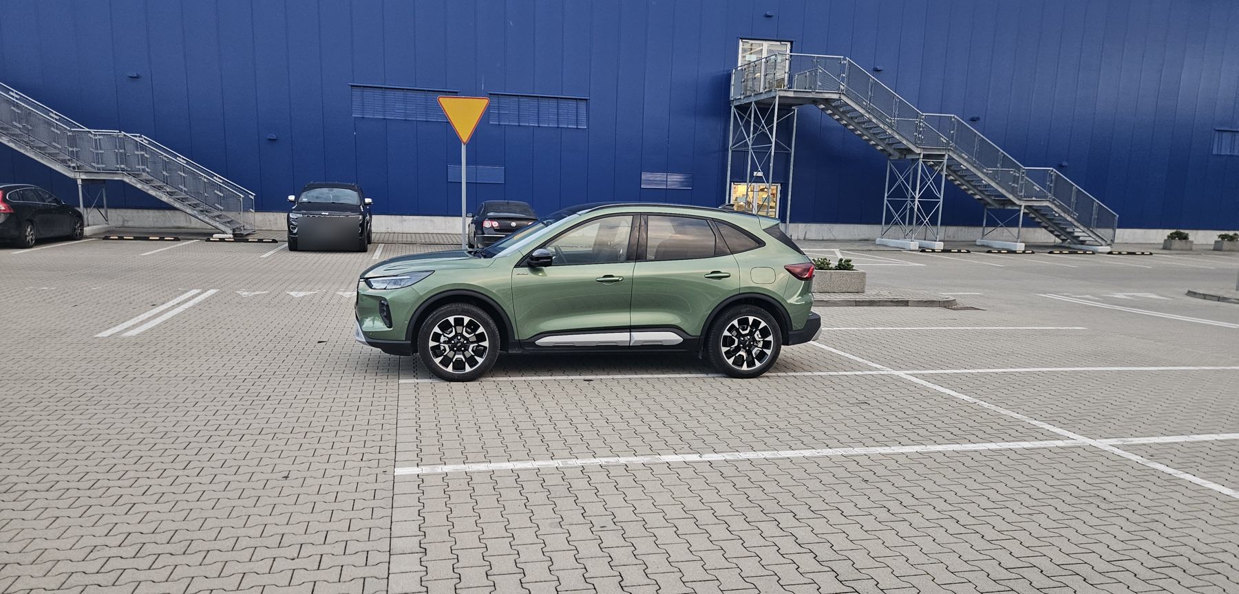 Zielona Ford Kuga z boku na parkingu